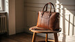 © Arslan - Brown leather tote bag sits on wooden stool in soft light. Ideal for luxury branding, product display, or advertising.