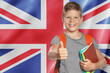 © New Africa - Little boy with backpack and notebooks showing thumbs-up against flag of United Kingdom. Language school