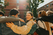© Maskot - Portrait of smiling young woman looking over shoulder while walking with arm around friends at street