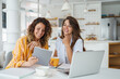 © Dorde - Two Female Friends Using Laptop And Tablet During Remote Work Meeting In Bright Contemporary Kitchen Space