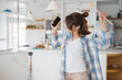 © Dorde - Carefree Young Woman Dancing And Singing With Smartphone In Bright Modern Kitchen Space Wearing Casual Attire