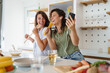 © Dorde - Young Women Enjoy Cooking and Singing Together in a Bright Modern Kitchen Setting
