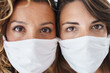 © Dorde - Two Caucasian Women Wearing White Masks Indoors with Expressive Eyes and Close-Up Focus