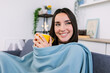© Xavier Lorenzo - Young pretty woman drinking hot coffee while sitting on sofa at home while looking out the window in winter day. Beautiful girl enjoying hot tea relaxing on couch in the living room