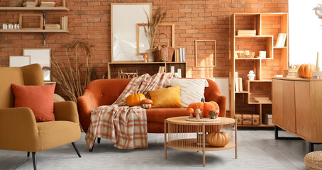 Poster - interior of cozy living room with autumn decor, red sofa and armchair