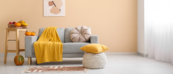 Poster - interior of cozy living room with sofa, pouf and pumpkins