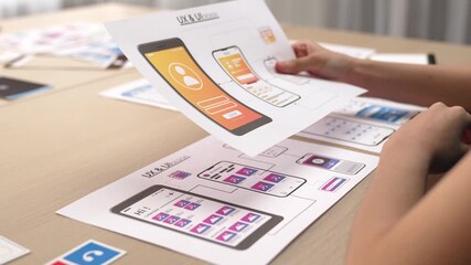 Startup company employee planning for user interface prototype for mobile application or website in office with model of program on desk. UX UI designer consider user friendly interface plan. Synergic