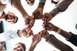 © Prostock-studio - Teamwork, Power And Partnership Concept. Below view of multucultural group of smiling people making fist bump standing in circle. Workers doing fist pump together celebrating good deal