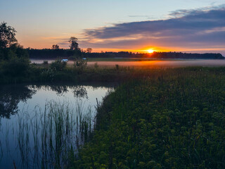 Wall Mural - a beautiful sunset over a lake with a reflection of the sun on the water. the sky is filled with clo