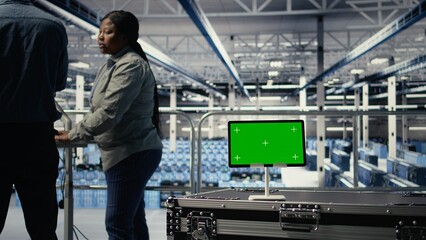 Data center IT professionals check AI dashboard using isolated screen tablet. Server room developers test artificial intelligence tools on chroma key device to ensure reliable performance, camera A