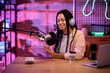 © Pixel-Shot - Female African-American radio presenter with clipboard recording broadcast at table in studio