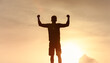 © kieferpix - silhouetted man stands with arms raised, showcasing triumph and freedom