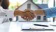 © anang - A handshake over paperwork, symbolizing a deal. A miniature house model sits in the background. Sunny, bright background with greenery