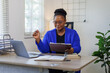 © David - Portrait of a cheerful excited happy businesswoman sitting at desk in modern office. Smiling african american executive using laptop while working from office with copy space.