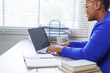 © David - African American business woman, A female secretary work on laptop Sitting at a Desk, reports to the workplace in the office, uses a computer
