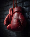 Red boxing gloves hanging against a dark, gritty brick wall