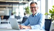 © Twig - Man in blue shirt smiles brightly while using a laptop in a bright office setting, with coworkers visible in the background
