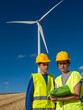 © Lester - Female engineer wearing safety gear instructing student near wind turbine, documenting training details on clipboard with expansive blue sky background