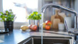 © Volodymyr Shcherbak - Close up shot of modern kitchen faucet with water running from tap, flow falling to empty dish sink at stylish home interior, selective focus, sustainable resources consumption concept