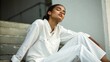 © Glory - Serene african american woman relaxing on steps in all white linen outfit embracing tranquility and natural light experiencing freedom