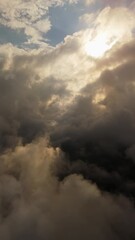Wall Mural - Dark storm clouds part as sunlight breaks through, captured in a vertical dolly shot.