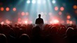 © Prayoga - A speaker on stage, silhouetted, before a large audience. Blurry background of stage lights