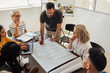 © Jacob Lund - Architects discussing design plans in a collaborative meeting at an architecture firm