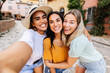 © Xavier Lorenzo - Selfie portrait of three young multiracial women having fun together at city during summer vacation in Italy. Holiday lifestyle and female friendship concept