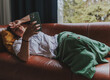 © olezzo - Sad mature woman lying on sofa in country house with mobile phone in hands