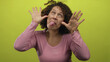 © Krakenimages.com - Middle aged woman pulls her hands to her ears while sticking out her tongue in a green studio setting; playfulness.