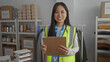 © Krakenimages.com - Woman in reflective vest taking notes at indoor charity center surrounded by donations depicting volunteer work and organization of supplies.