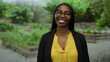 © Krakenimages.com - Woman smiling in outdoor park setting with greenery, wearing glasses and yellow shirt, exudes happiness and confidence in natural light.