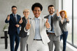 © Novak - A group of diverse business professionals standing together in a modern office environment. The team looks confident and approachable