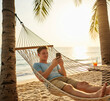 © Metehan - young man or boy with mobile phone in summer lying in hammock