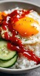 © Jufri - Bowl of rice, egg, and tomato sauce.  Fresh, sliced cucumbers are visible