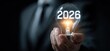 © brokglas - Businessman holds illuminated lightbulb with the year 2026 displayed, symbolizing future ideas and innovation
