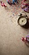 © Wan - Vintage alarm clock on a textured surface, surrounded by colorful confetti and ribbons