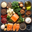 © Haza - A colorful assortment of nutritious foods, including salmon, cheese, broccoli, nuts, and more, arranged on a dark gray surface, showcasing a balanced diet.