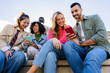 © Xavier Lorenzo - Group of young multiracial students sharing a moment outdoors while looking at a smart phone screen. Youth community, friendship and lifestyle concept.