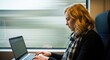© Nimra - Woman with blonde hair using laptop on a moving train with blurred background outside the window