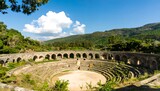 An ancient amphitheater with arched stone bridges and lush green hills, bathed in sunlight.