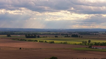 Wall Mural - Sky with clouds with rays of sun shining through falling on the landscape of fields and meadows. Sunny day in the Czech Republic