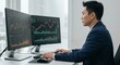© Herlita - A focused individual analyzes financial charts on a dual-monitor computer setup, showcasing a professional and attentive demeanor.