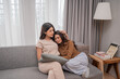 © Odua Images - Two women share a warm, intimate moment on a cozy sofa, highlighting friendship.