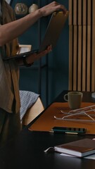 Wall Mural - Vertical shot of male freelance worker sitting down at table with wireless laptop in home office