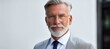 © Ilja - Confident mature businessman with gray hair and beard smiling in his modern office environment.