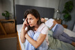 © Stockphotodirectors - A woman sits on the edge of the bed, deep in thought, while her partner sleeps nearby, highlighting feelings of tension and uncertainty in their relationship.