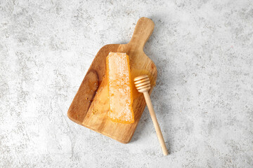Wall Mural - Wooden board with fresh honeycomb and dipper on light background