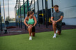 © DusanJelicic - Young sporty man and a woman performing lunges together on an outdoor gym turf. They are both dressed in athletic wear and appear to be in the middle of a workout session.