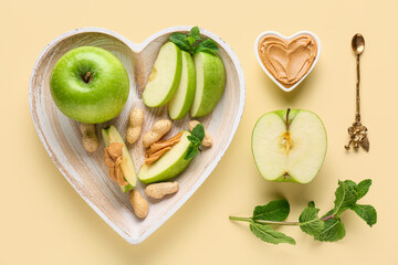 Wall Mural - Plate with cut fresh apple, mint and bowl of sweet peanut butter on yellow background